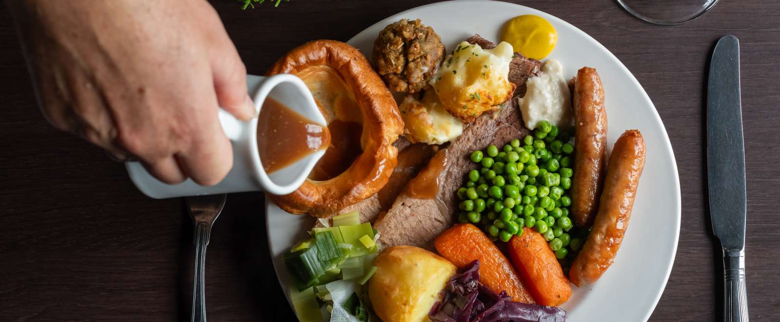 Lady pouring gravy on beef carvery at Carriages Brasserie 
