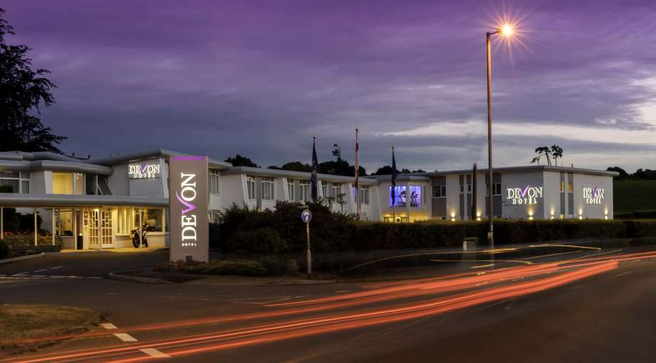 Devon Hotel Exterior with Sign and Flags at Night