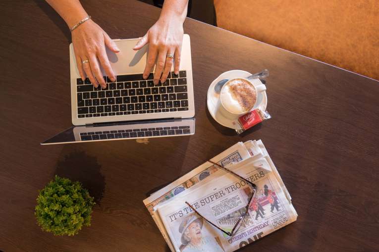 Devon Hotel Woman Typing on Laptop with a Coffee