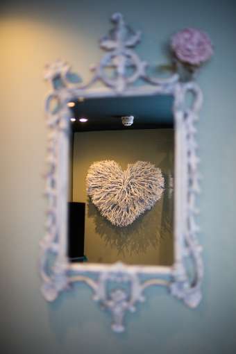 ornate mirror showing a heart on wall in reflection