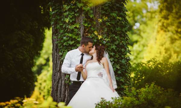 Bride and groom kissing outdoors by a tree