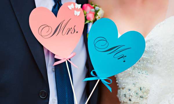 A bride and groom holding mrs and mr love heart signs