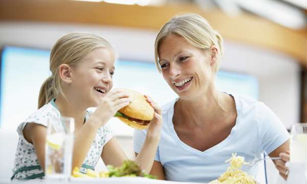 child eating burger with mother