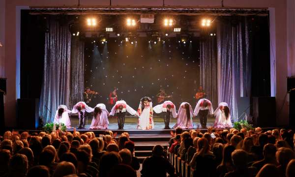 A collective of musicians, singers and dancers in gypsy costumes perform on stage