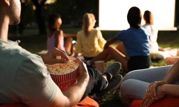 People watching outdoor cinema with popcorn