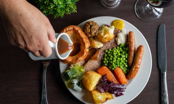 Lady pouring gravy on beef carvery at Carriages Brasserie 
