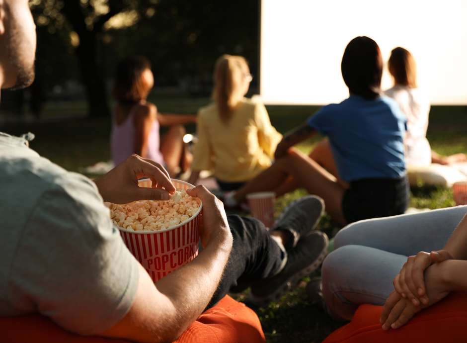 People watching outdoor cinema with popcorn