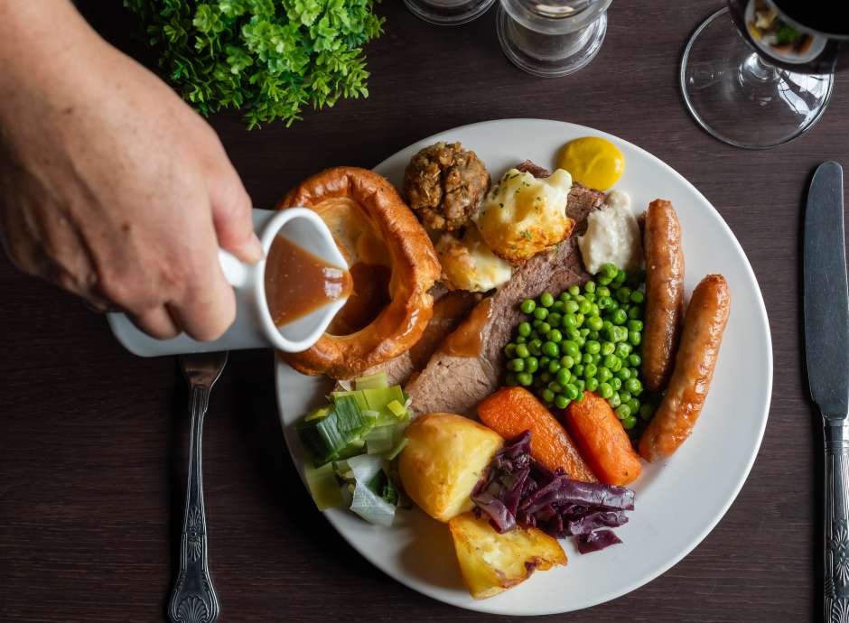 Lady pouring gravy on beef carvery at Carriages Brasserie 