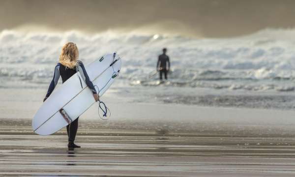 Girl walking to the sea with surfboard 